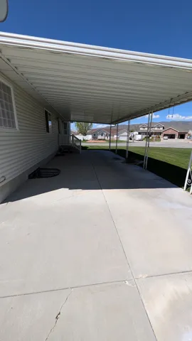 Expansive concrete driveway featuring a metal carport structure