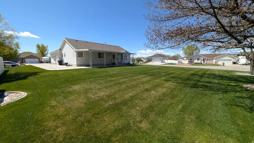 Spacious backyard featuring a manicured lawn, a concrete patio, and a light-colored siding exterior