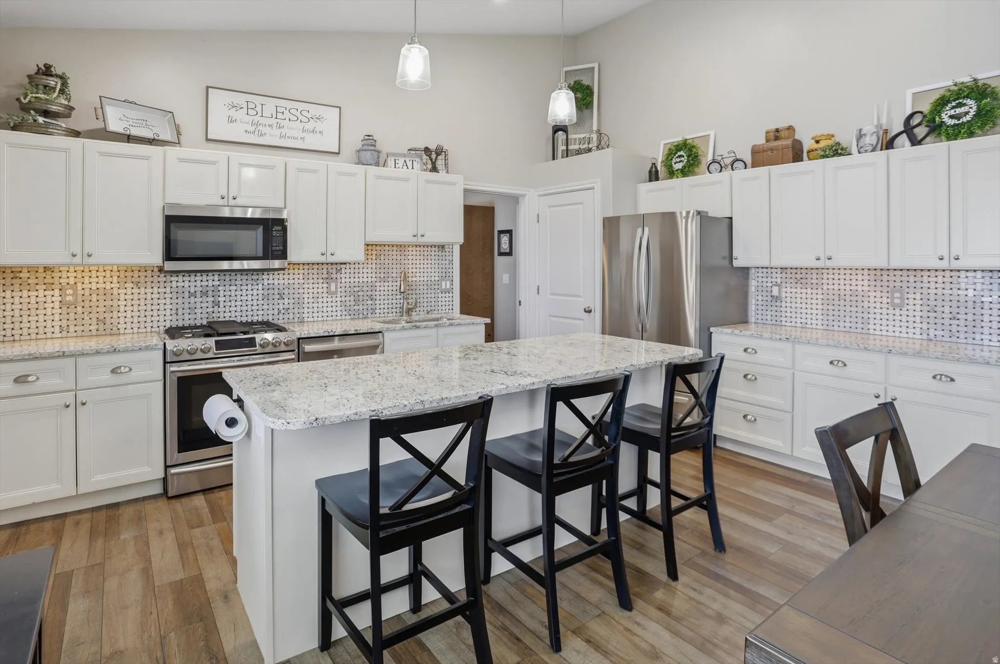 Open concept kitchen featuring white cabinetry, light-toned countertops, stainless steel appliances, and wood-finish flooring