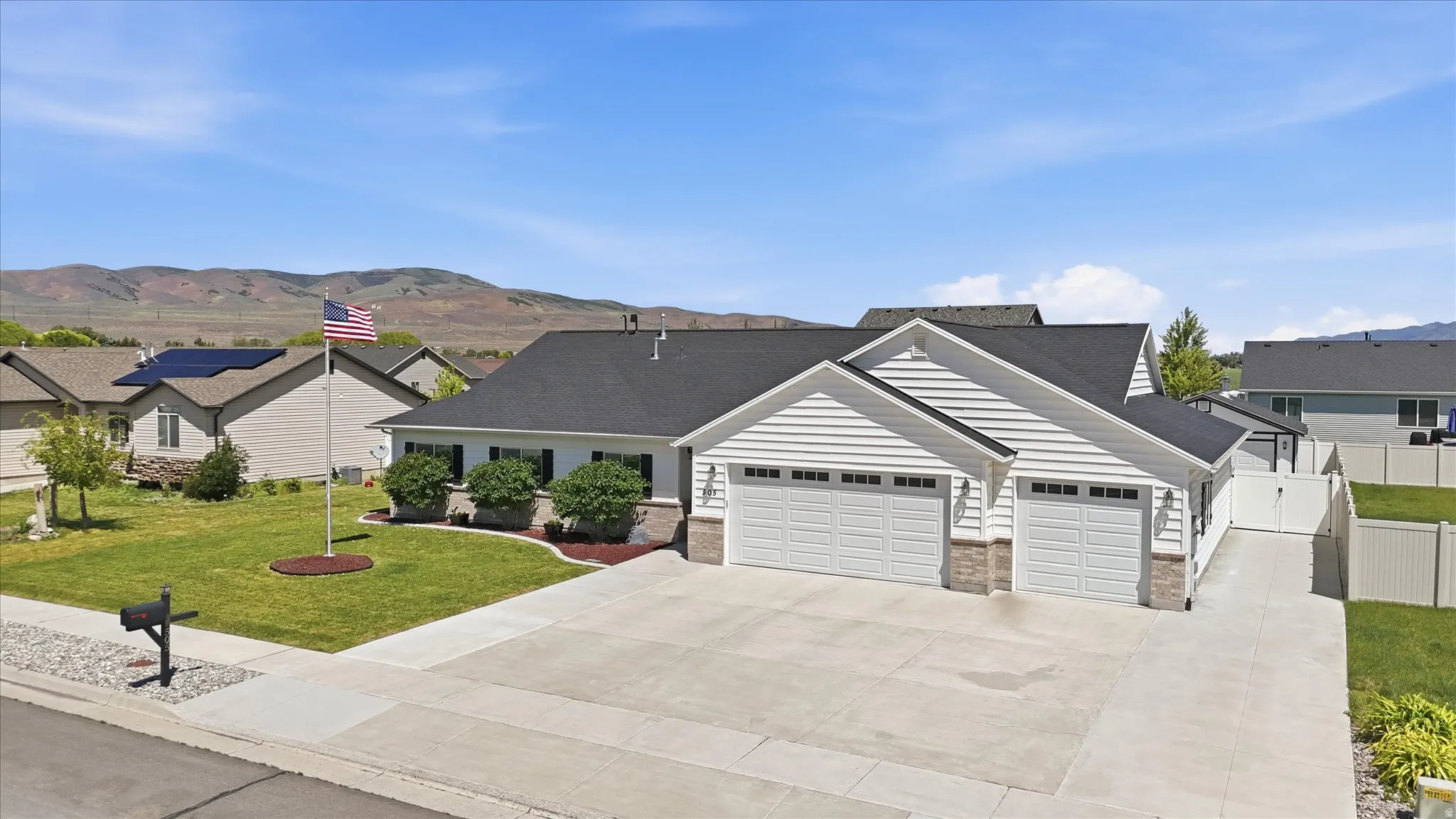 Contemporary ranch-style residence featuring white horizontal siding, a dark roof, and stone accents