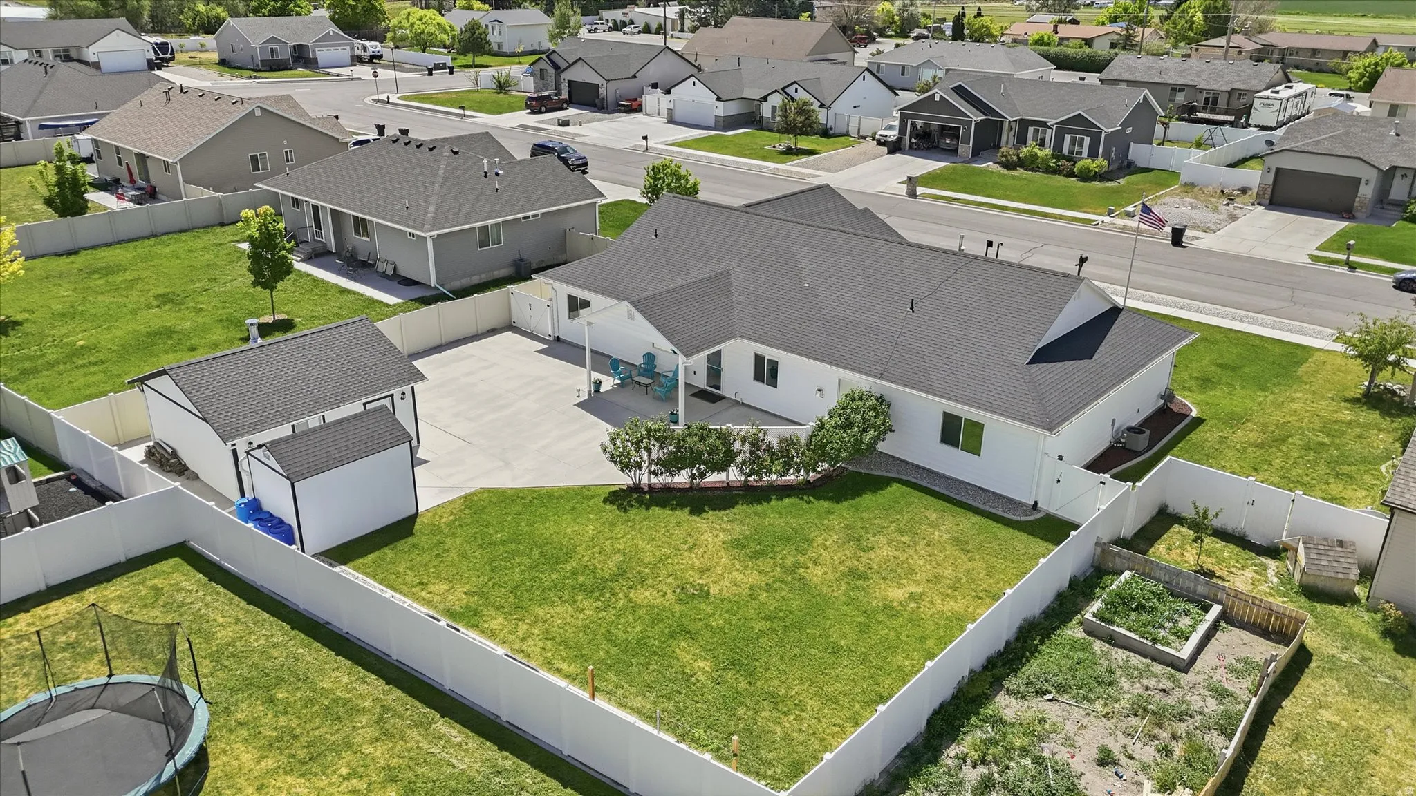 Expansive property featuring a large backyard with a lawn area, a dedicated garden bed, a substantial detached outbuilding, and a separate storage shed