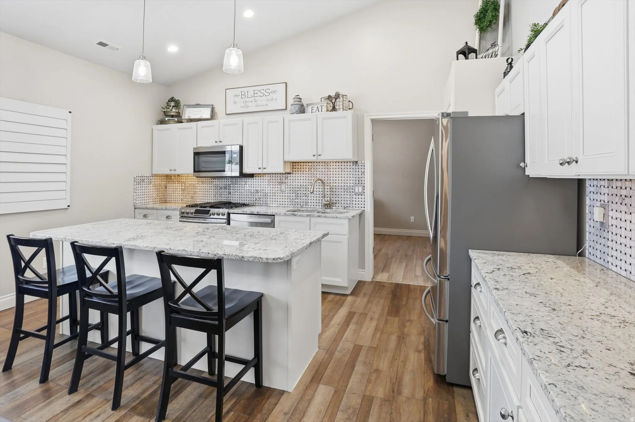 Kitchen featuring white shaker cabinetry, stainless steel appliances, speckled countertops, and a full-height tiled backsplash