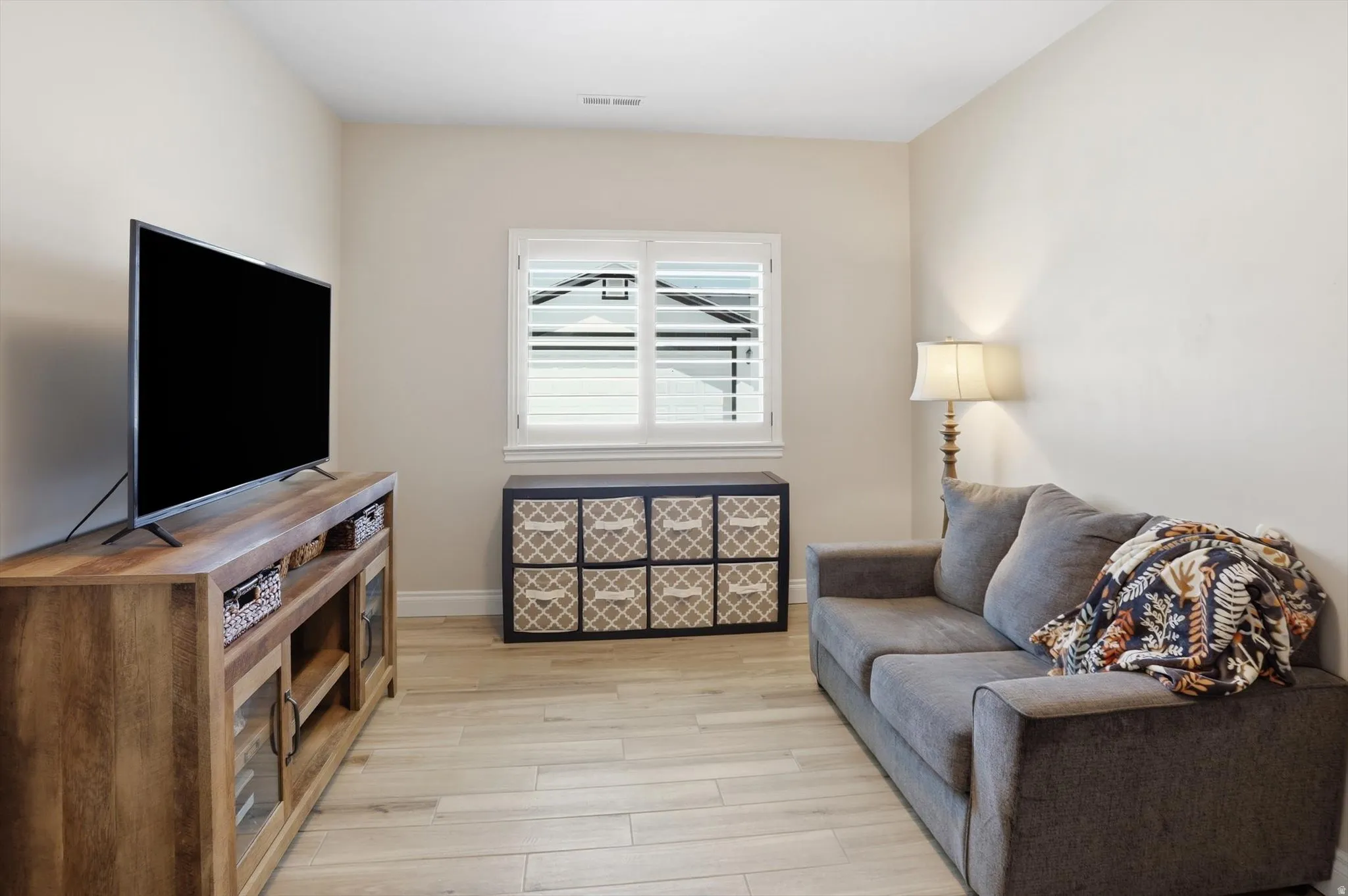 Room featuring wood-finish flooring, a window with louvered shutters, and light-toned wall paint