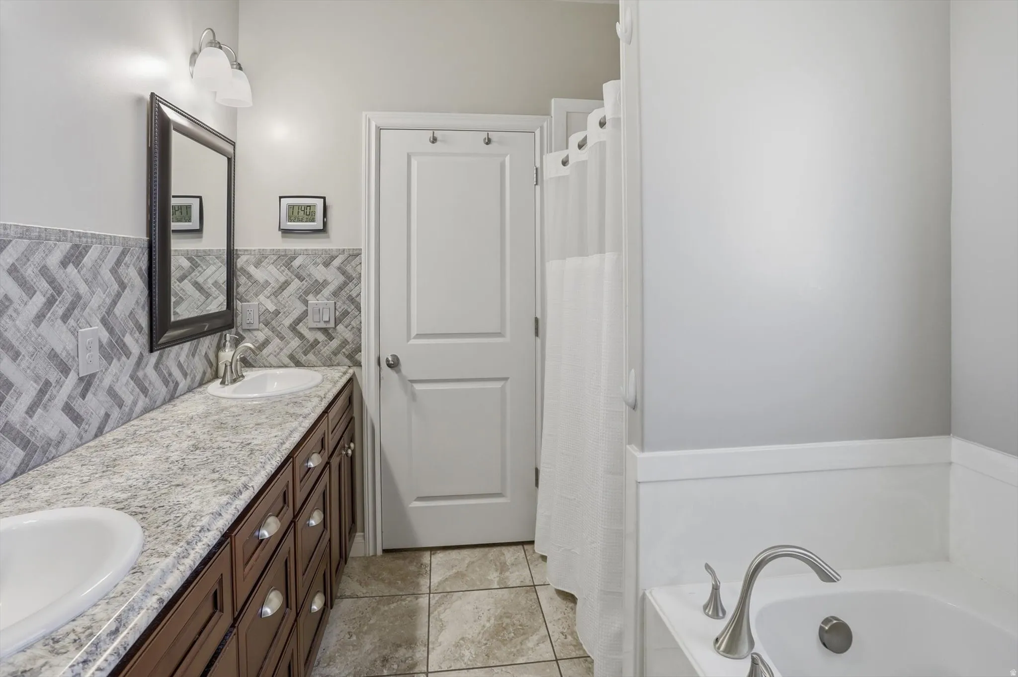 Bathroom featuring a double vanity with dark wood-finish cabinetry, a light speckled countertop, and dual oval undermount sinks