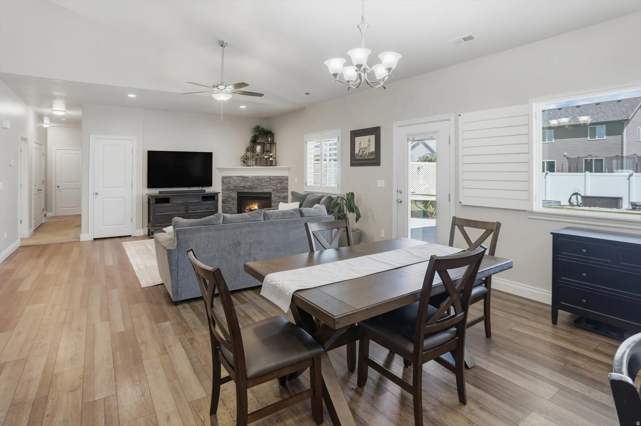 Open-concept living space featuring wood-finish flooring, a stone-faced fireplace, and recessed lighting