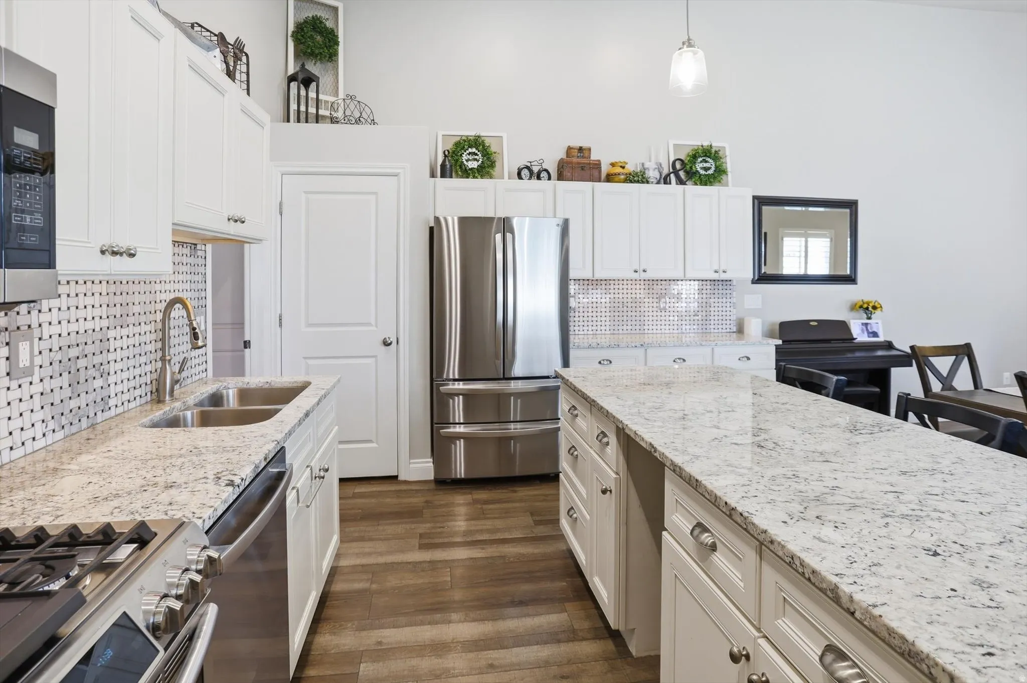 Kitchen featuring white cabinetry, stainless steel appliances, speckled stone countertops, and wood-finish flooring