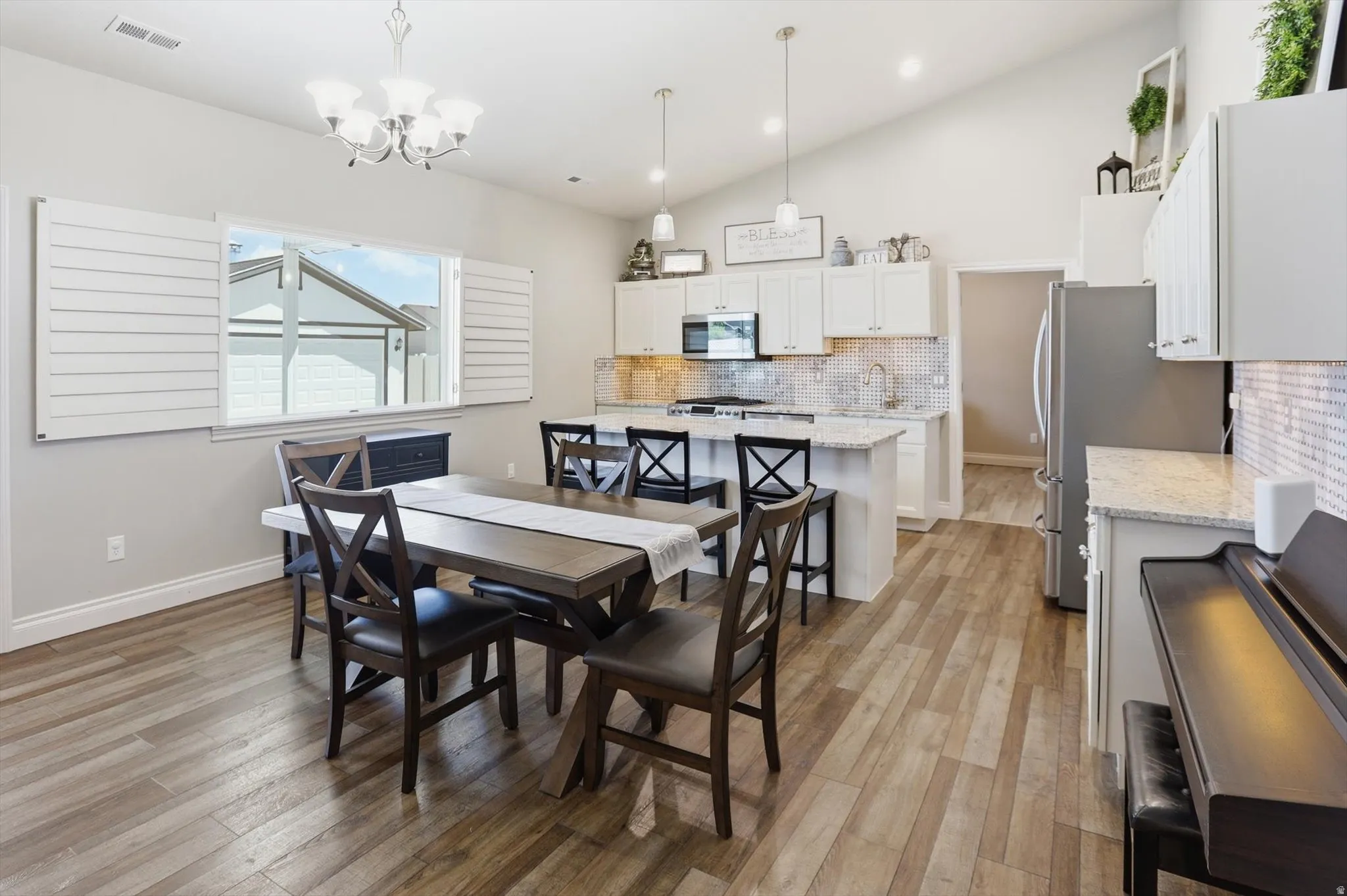Open-concept kitchen and dining area featuring wood-finish flooring, vaulted ceilings, and recessed lighting