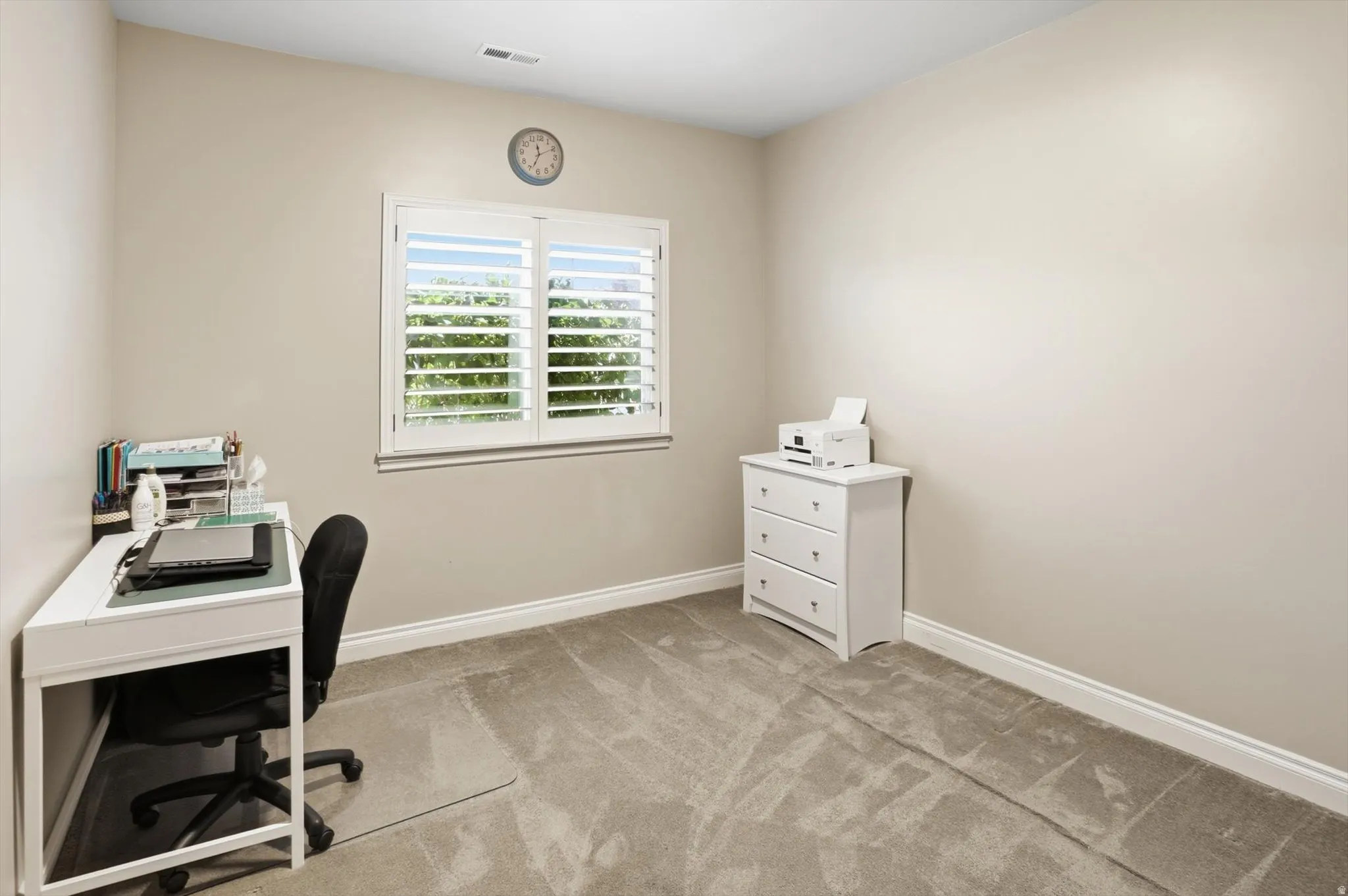 Neutral-toned room with a window featuring white plantation shutters