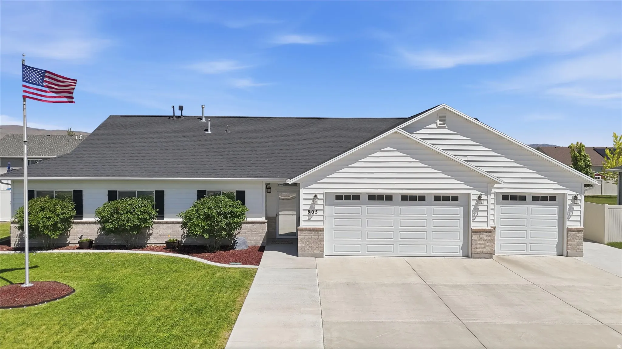 Ranch-style exterior featuring white siding, a dark shingle roof, and a three-car garage