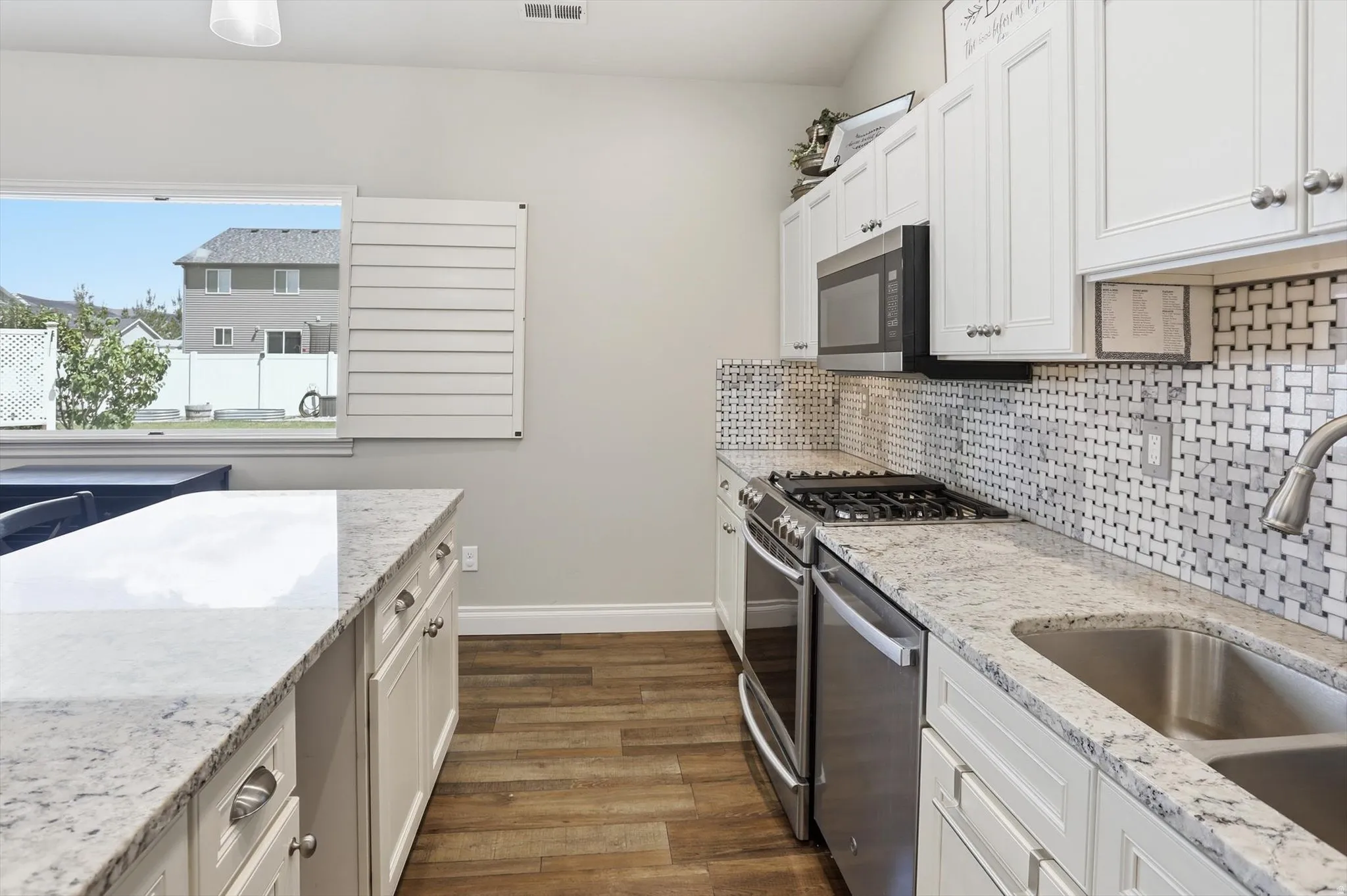 Kitchen featuring light-toned cabinetry with coordinating hardware, stainless steel appliances, and wood-finish flooring