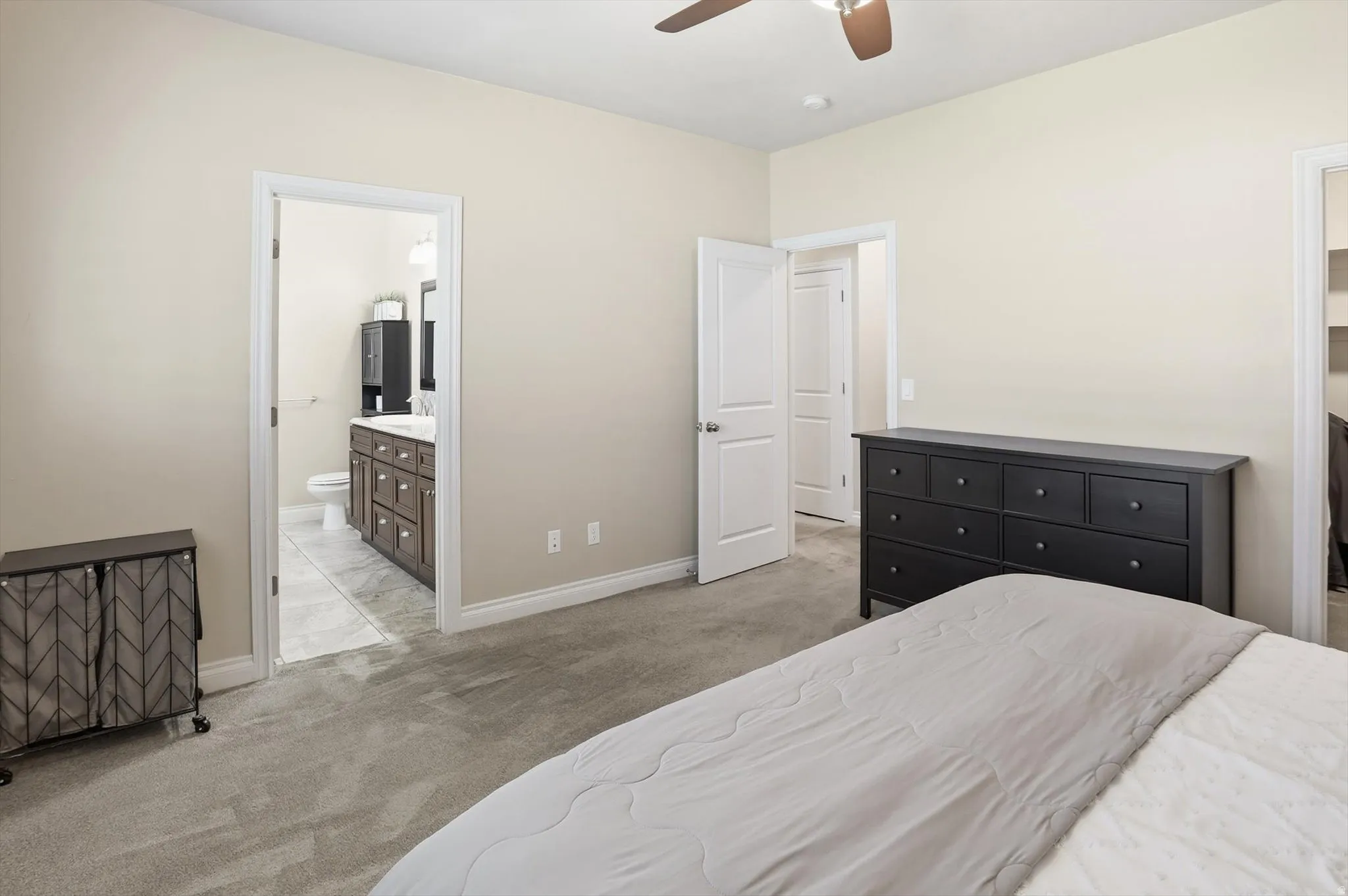 Carpeted bedroom with a ceiling fan, light-toned walls, and white trim