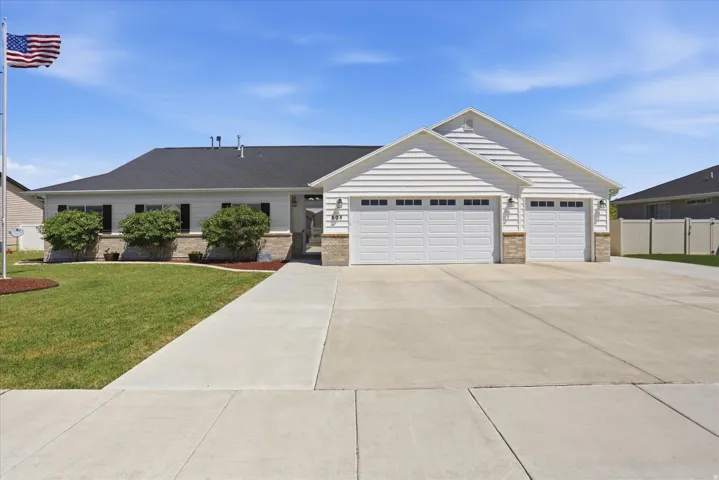 Front exterior featuring white horizontal siding, a dark asphalt shingle roof, and stone facade accents