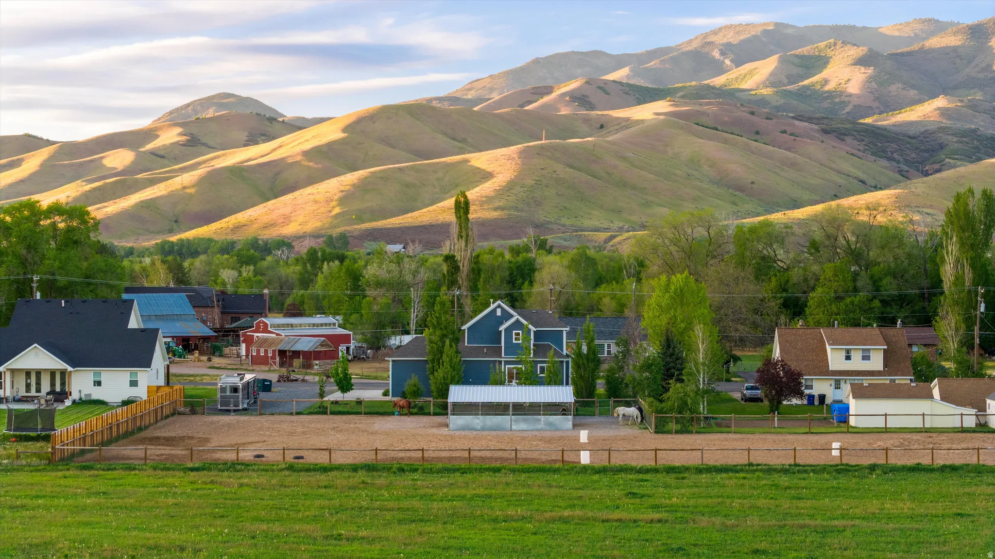 Expansive property featuring a large equestrian riding arena, white fencing, and a variety of mature trees