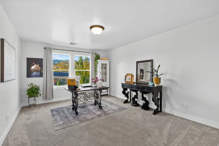 Spacious room featuring broad windows, light gray carpet, white walls, and a semi-flush mount ceiling light