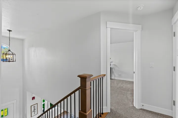 Staircase featuring wood-finish handrail, black balusters, and white risers