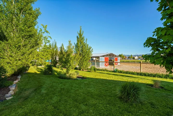 Expansive backyard featuring a manicured lawn, established trees, and natural stone landscaping
