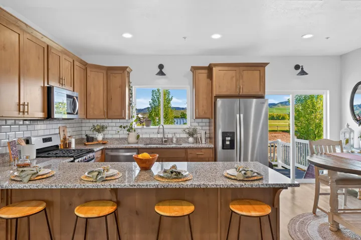 Kitchen featuring granite countertops, wood cabinetry, stainless steel appliances, and a subway tile backsplash