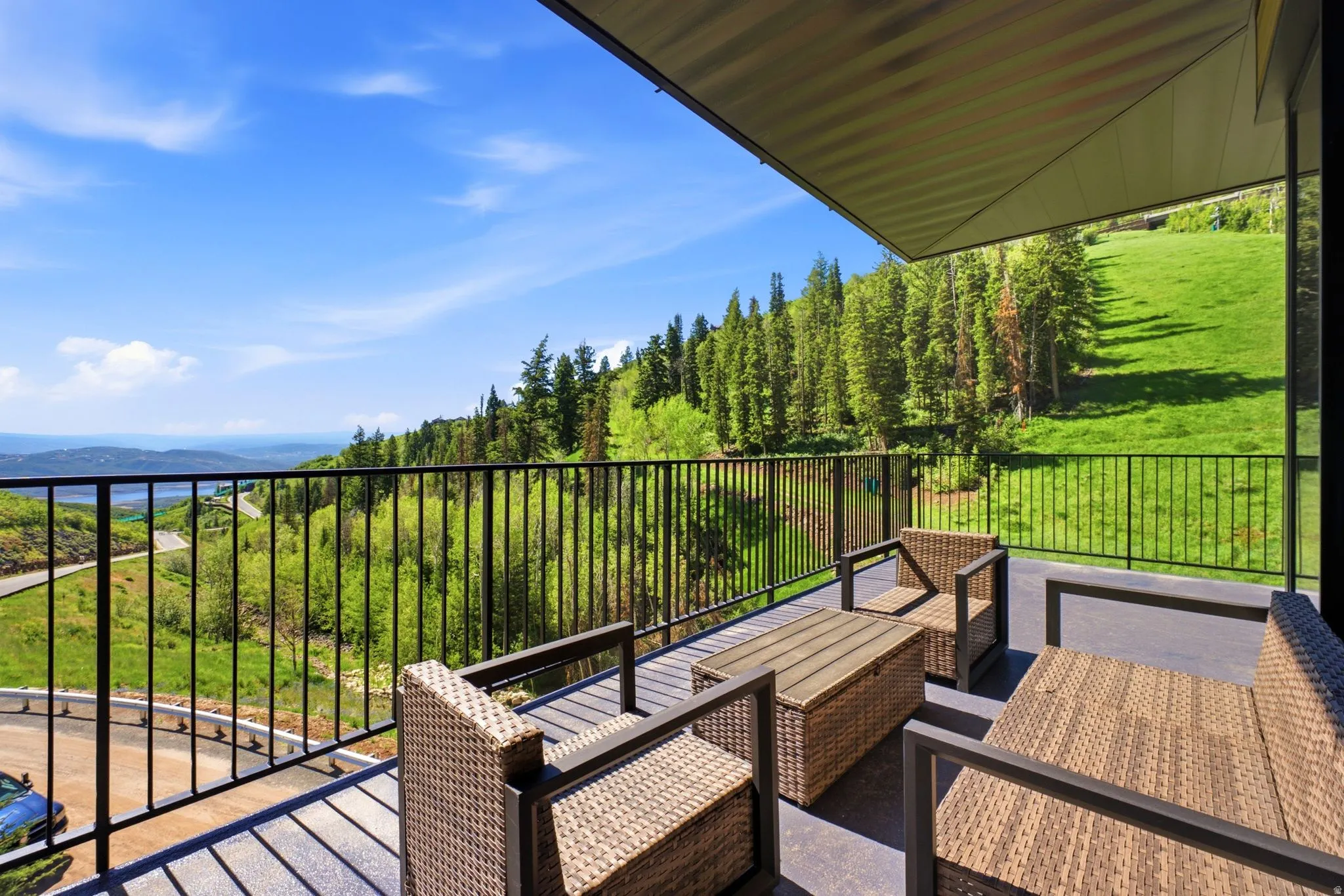 Spacious outdoor balcony with a black metal railing and a partial overhead covering