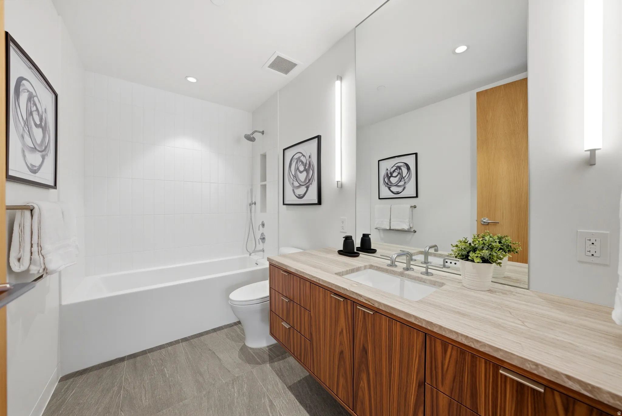 Contemporary bathroom featuring a wood-finish vanity, integrated sink, and stone countertop