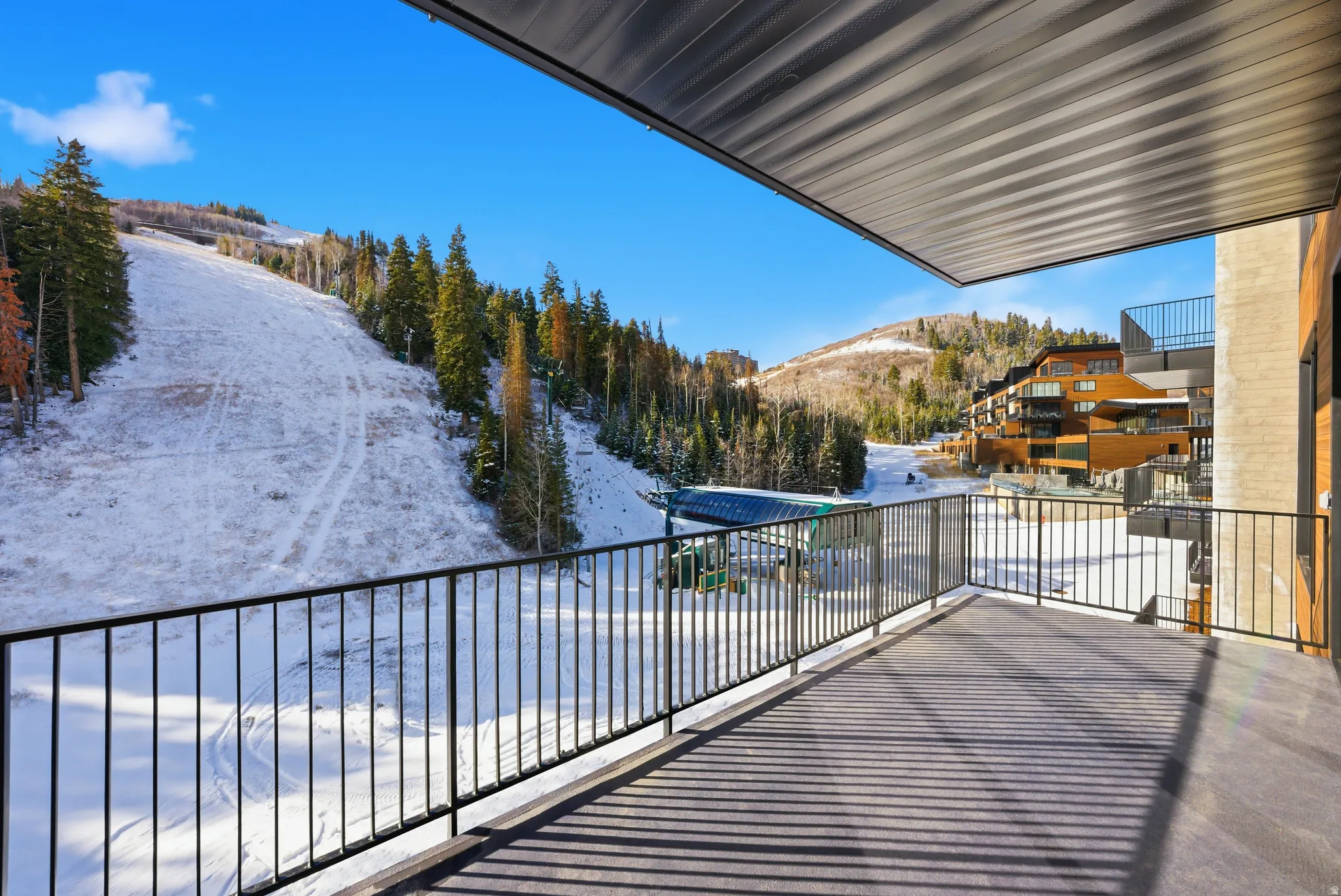 Spacious outdoor balcony with a black metal railing and a textured overhead covering