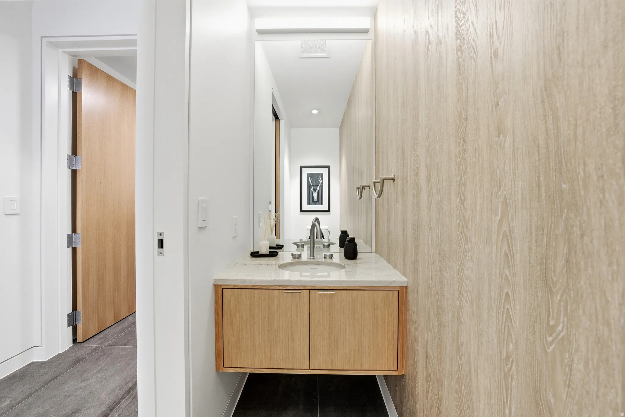 Modern bathroom vanity featuring a light wood-finish floating cabinet with two doors, a light-toned countertop, and a rectangular undermount sink