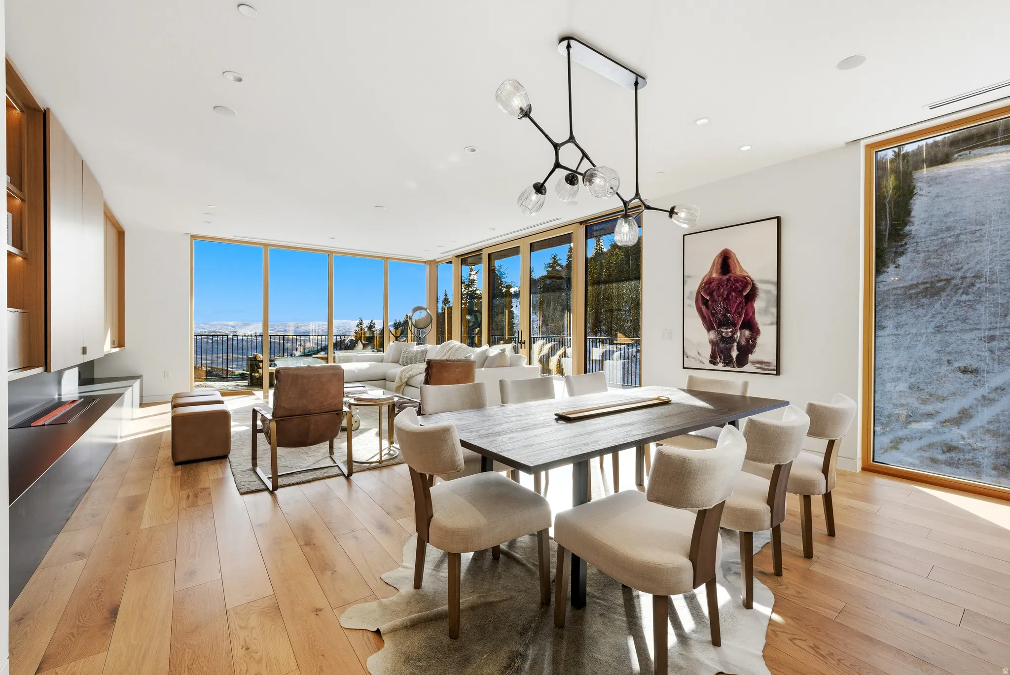 Open-concept living space with expansive floor-to-ceiling windows, wood-finish flooring, and recessed lighting