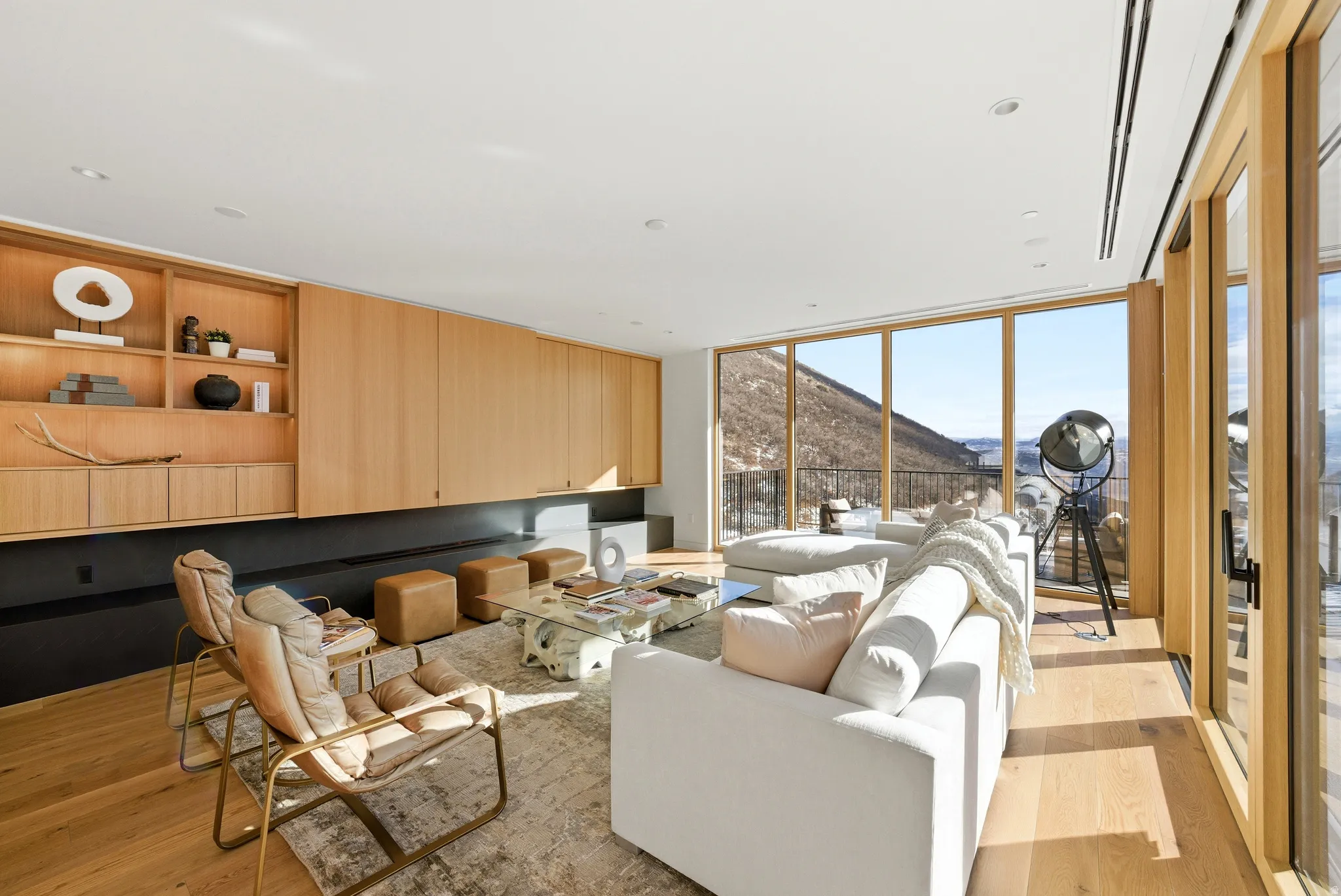 Spacious living area featuring extensive wood-finish flooring, a full wall of custom built-in cabinetry and shelving, and large sliding glass doors