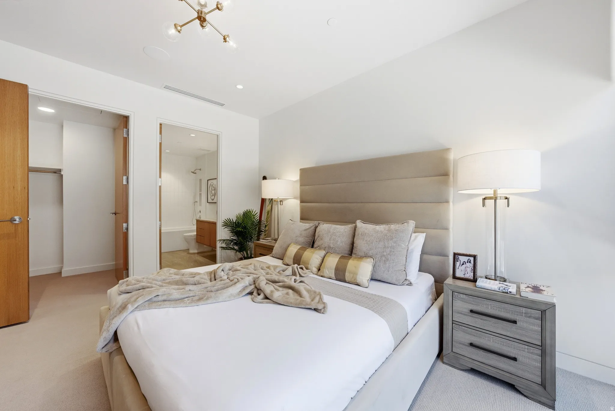 Carpeted bedroom featuring a built-in upholstered headboard, a modern ceiling light fixture, and recessed lighting