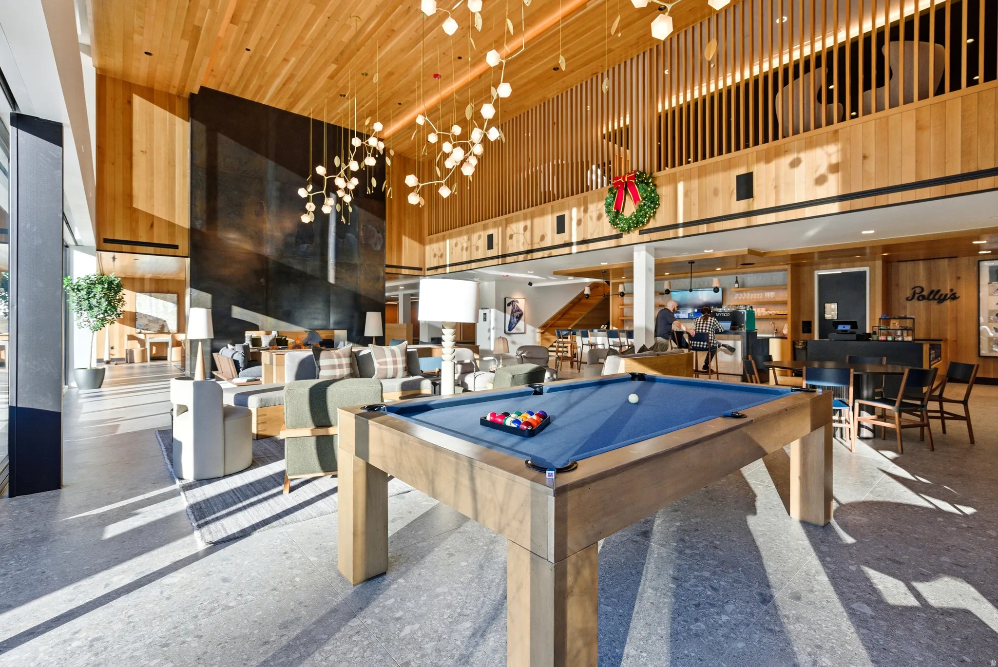 Spacious common area featuring a billiards table, high ceilings with wood paneling, contemporary light fixtures, a large dark accent wall, and a multi-level layout