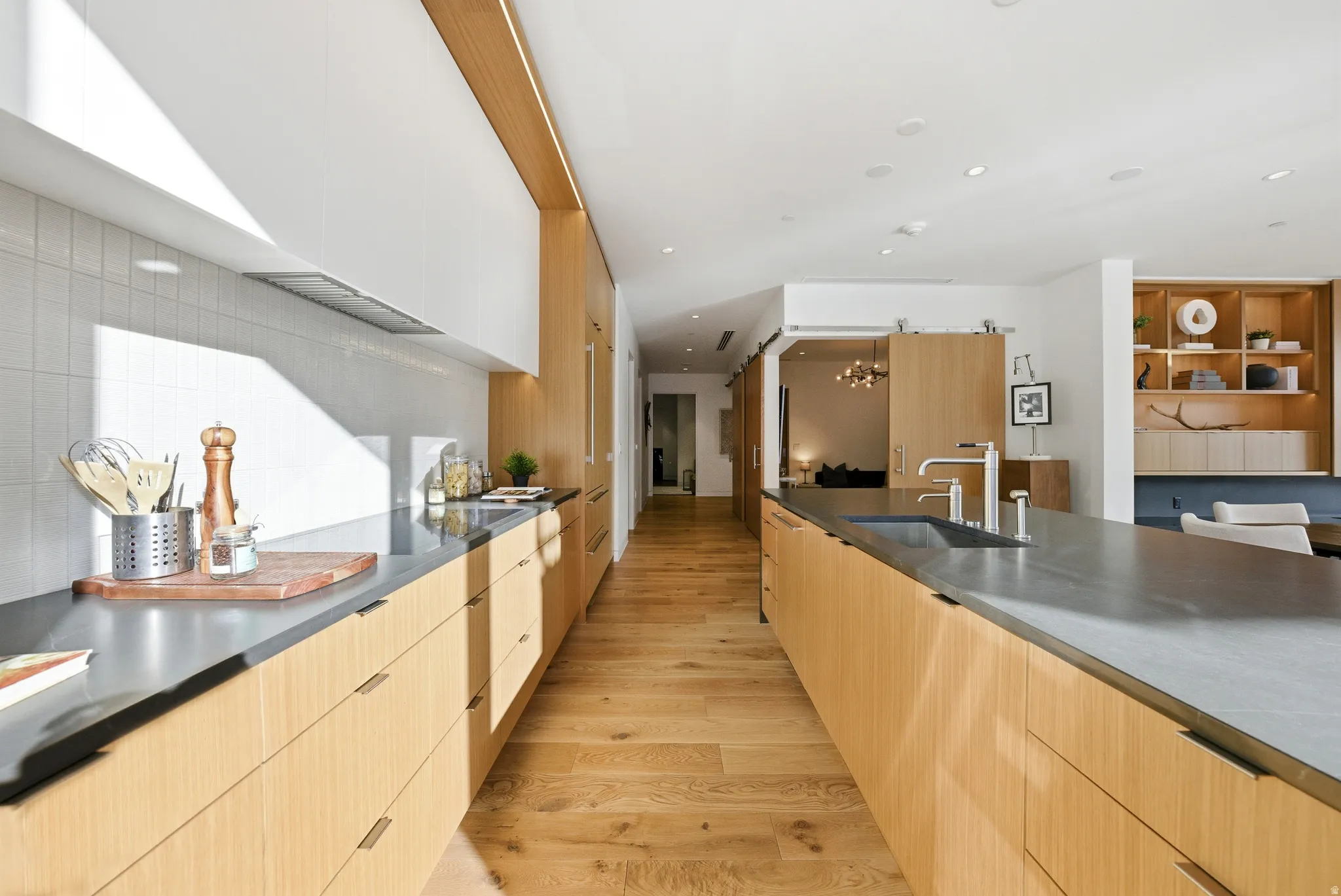 Modern kitchen featuring wood-finish flooring and extensive light-toned cabinetry