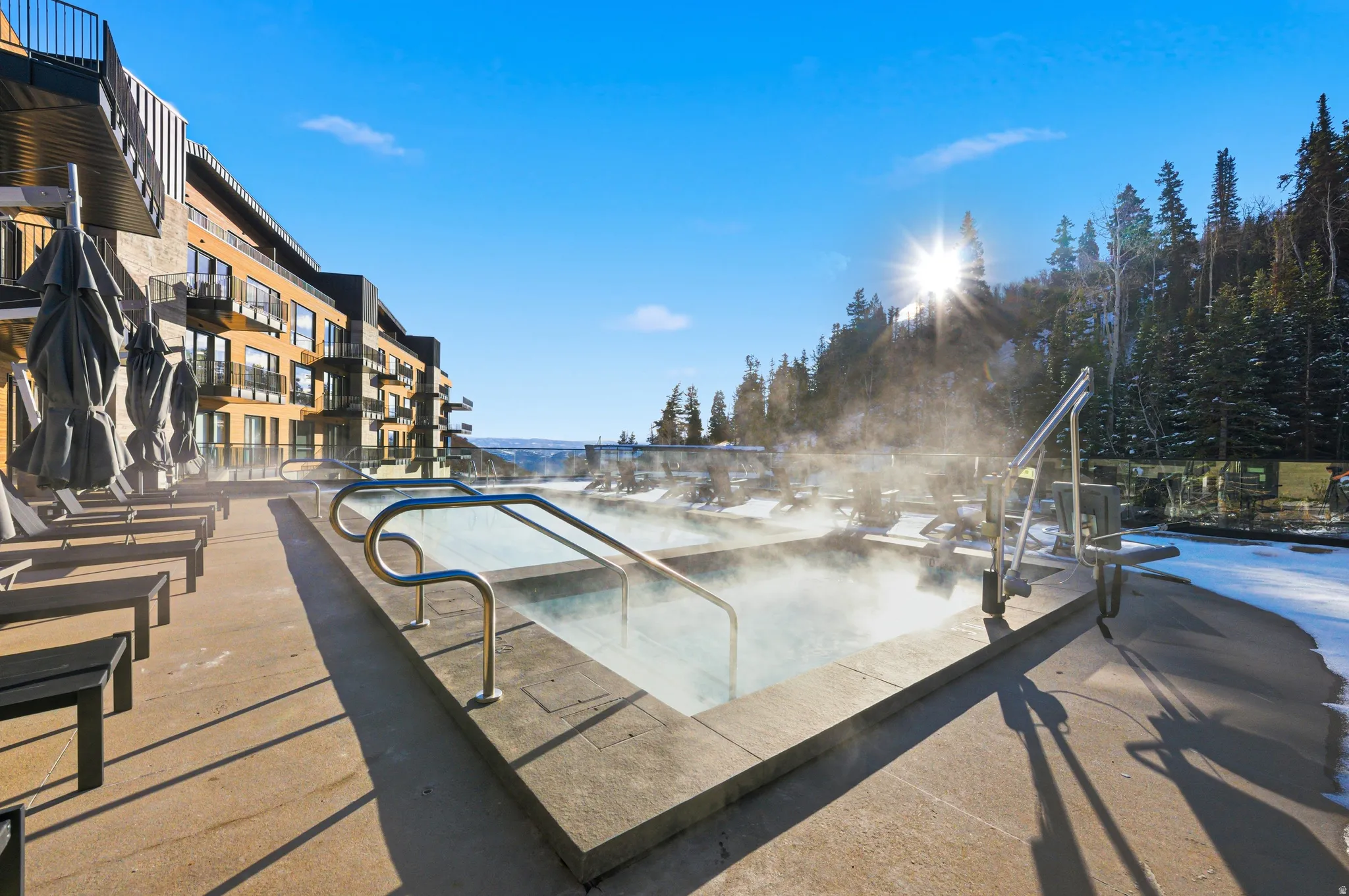 Outdoor heated pool area with concrete decking and adjacent lounge seating
