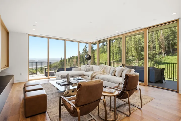 Expansive living area featuring wood-finish flooring and floor-to-ceiling glass doors opening onto a balcony