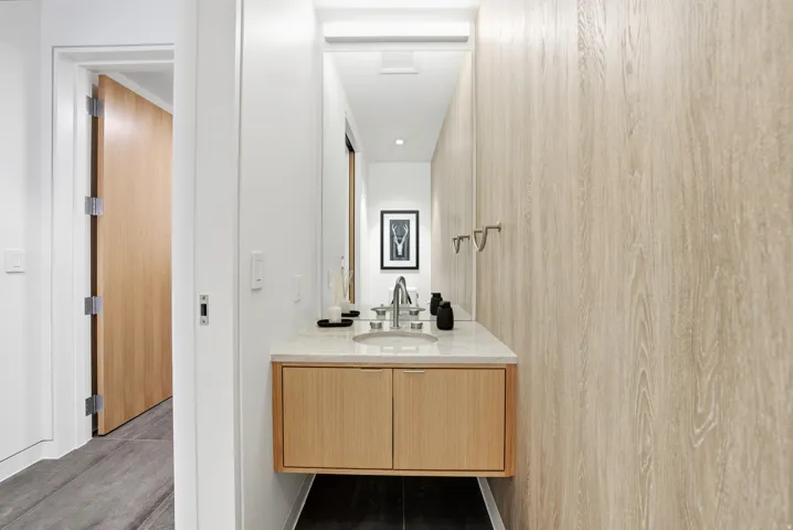 Modern bathroom vanity featuring a light wood-finish floating cabinet with two doors, a light-toned countertop, and a rectangular undermount sink