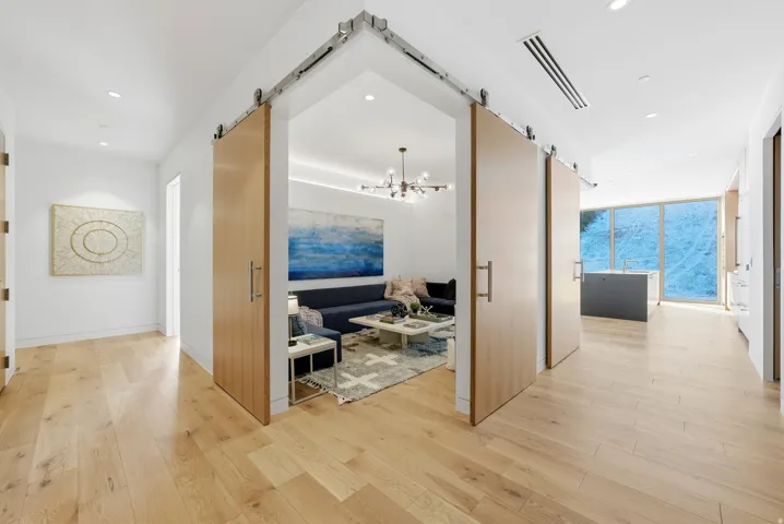 Corridor with a barn door, light wood-style flooring, expansive windows, and suspended lighting