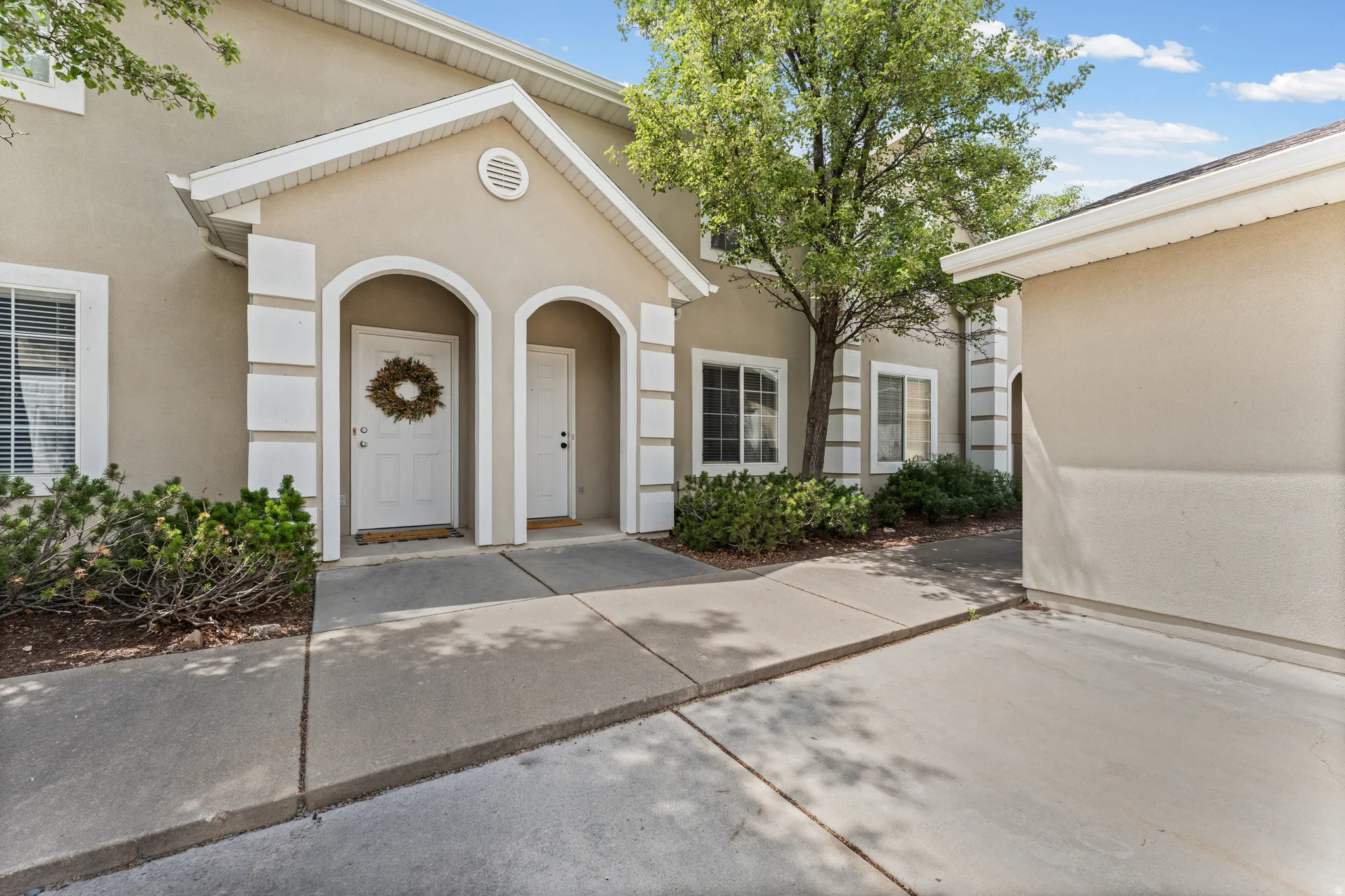 Exterior entry featuring twin arched doorways, a gabled portico, and decorative pilasters