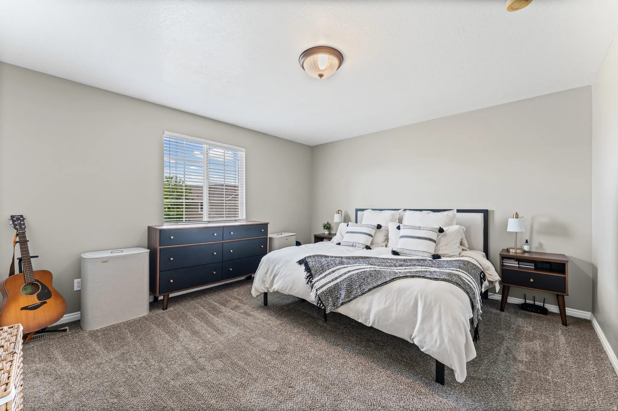 Carpeted bedroom featuring a flush mount ceiling light fixture, a window with blinds, and light gray wall paint