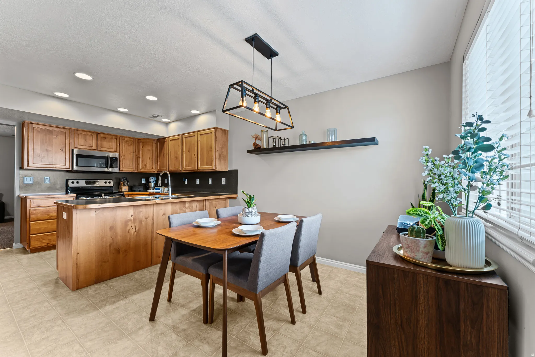 Open concept kitchen and dining area with wood cabinetry, stainless steel appliances, and a central island