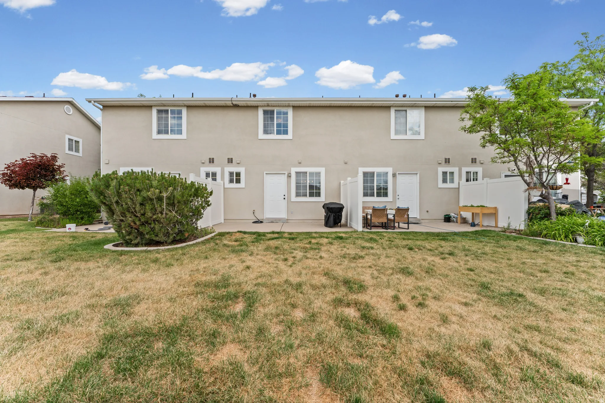 Rear exterior with a concrete patio, multiple windows, and a partially fenced yard
