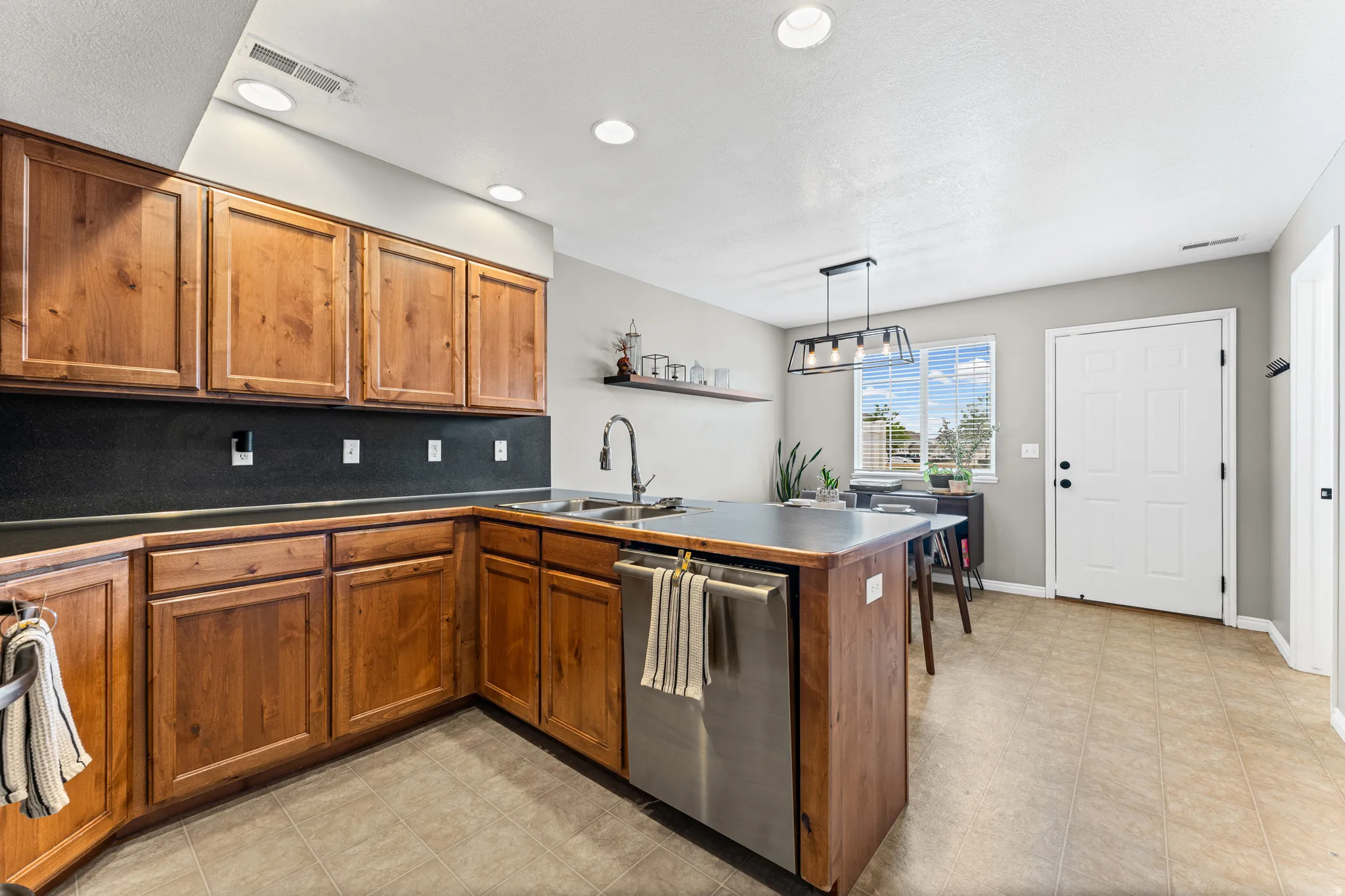 Kitchen featuring abundant wood cabinetry, an island with integrated stainless steel dishwasher, and stone-look countertops