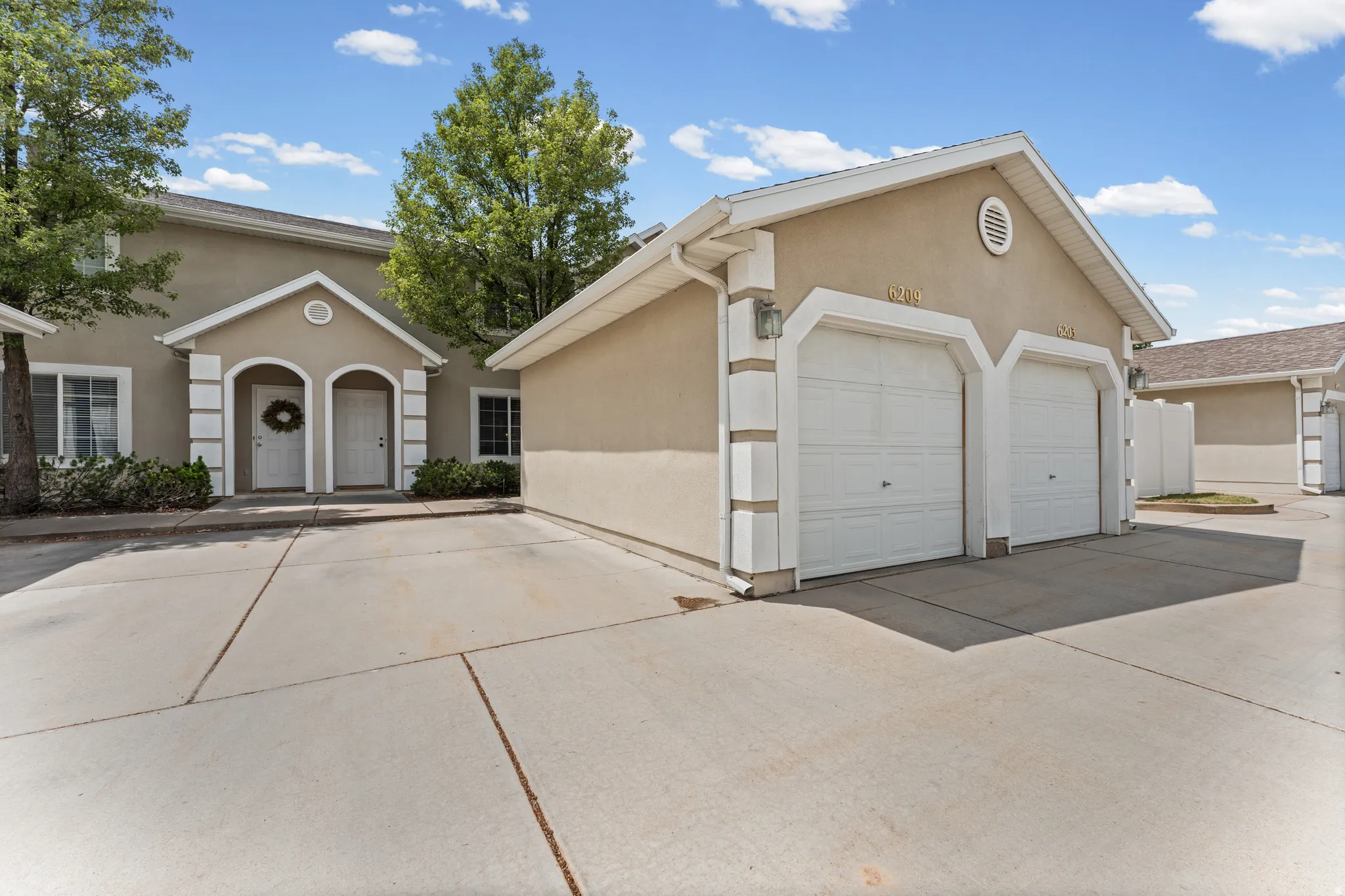 Stucco exterior featuring dual arched entryways and an attached two-car garage with panel doors