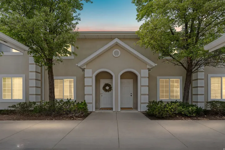 Two-story stucco facade featuring symmetrical entryways with arched alcoves, decorative columns, and gabled porticos