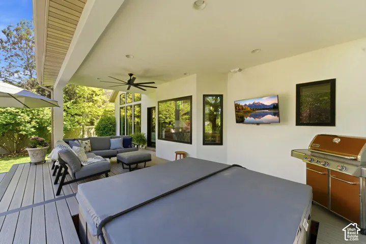 Expansive covered patio featuring a hot tub, built-in grill, and ceiling fan