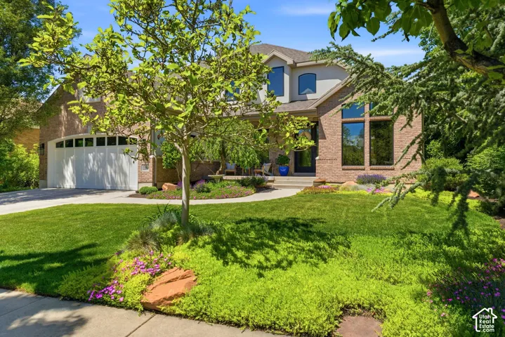 Brick-front residence featuring a two-car garage with arched windows, a multi-pane glass entry door, and varied rooflines