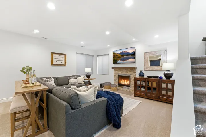 Living area featuring a stacked stone fireplace with a wood-finish mantel, recessed lighting, and light-colored carpeting