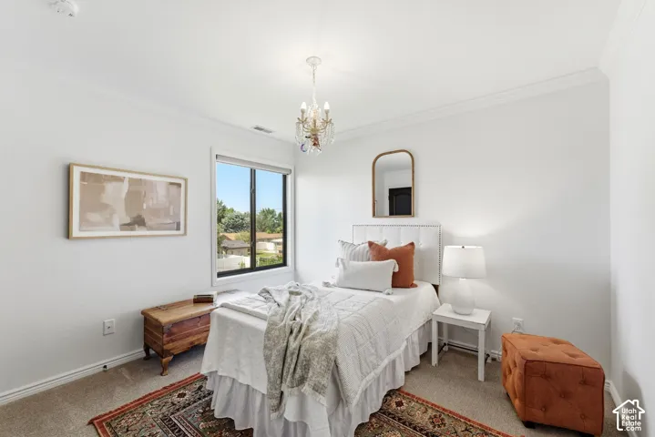 Bright room featuring a large window, crown molding, a built-in chandelier, and neutral-toned carpeting