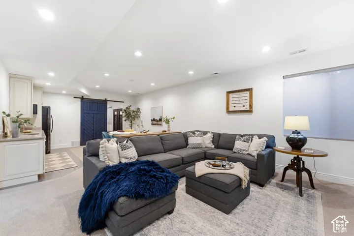 Open-concept living space featuring recessed lighting, a built-in wet bar with light-toned cabinetry and a stone countertop, and a dark blue sliding barn door