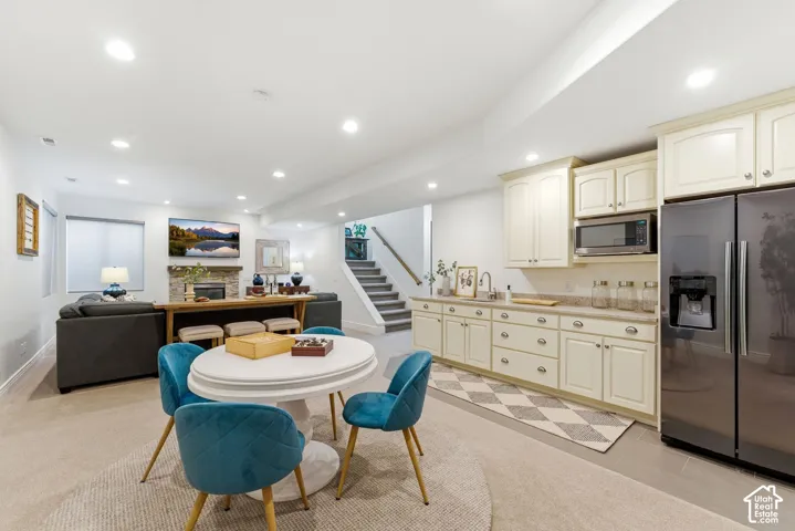 Spacious lower-level living area featuring a built-in wet bar with cream cabinetry, a stainless steel refrigerator, and a microwave