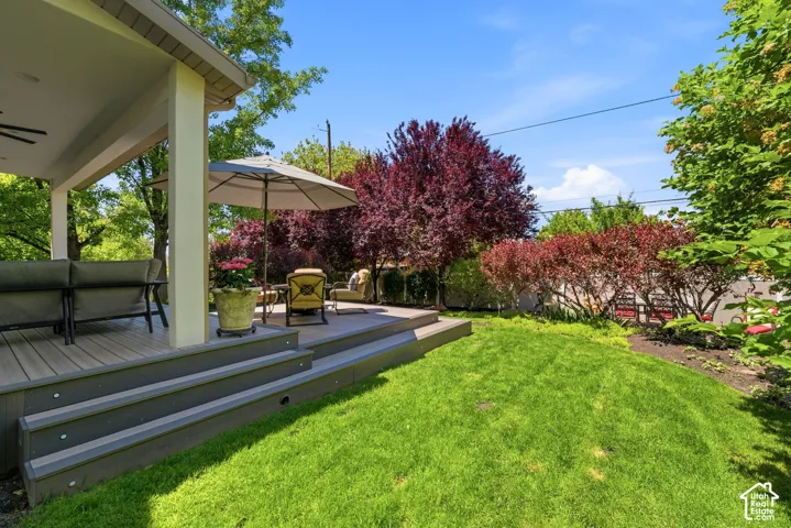 Expansive tiered deck featuring composite decking, integrated step lighting, and a covered patio area with a ceiling fan