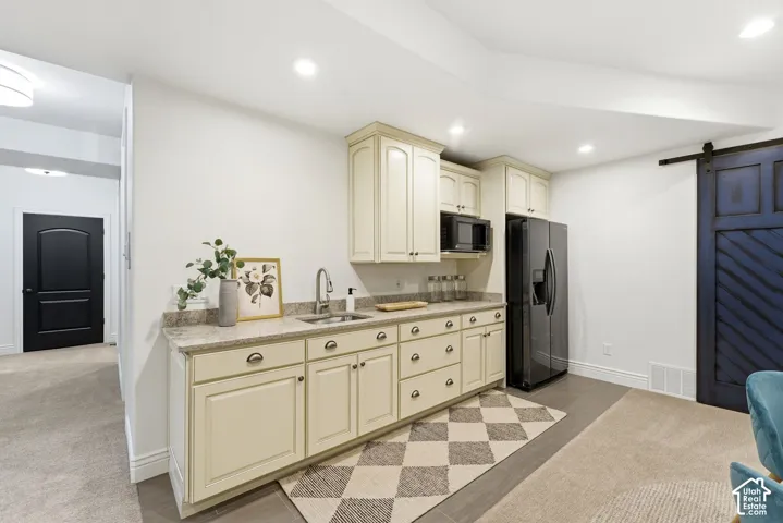 Kitchenette featuring cream-colored cabinetry, a built-in microwave, and a black refrigerator