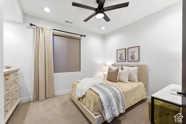 Carpeted room featuring a ceiling fan with integrated lighting, recessed lighting, and a window with roller shade and drapes